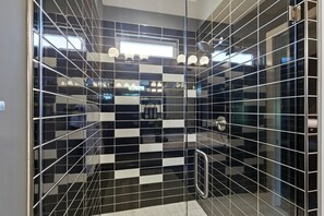 A modern bathroom with black and white checkered tiles, a glass shower enclosure, and a visible towel rack.