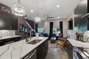 A modern kitchen with a marble countertop, a built-in oven, and a dining area with a wooden table and chairs.