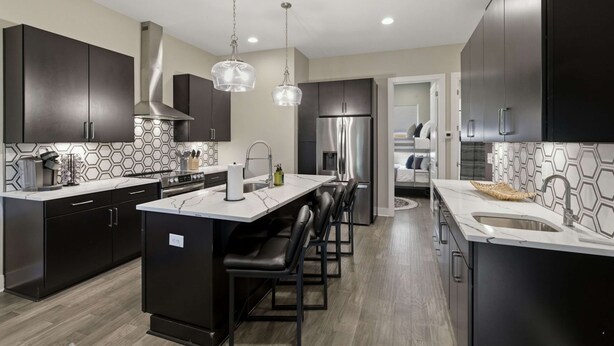 A modern kitchen with dark cabinetry, a central island with bar stools, stainless steel appliances, and pendant lighting. - Rooftop Views, 4BR 4BA, 7 Beds, Near Broadway! (Nashville)