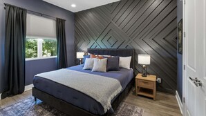 A modern bedroom with a bed, nightstands, and a geometric-patterned wall. - Rooftop Views, 4BR 4BA, 7 Beds, Near Broadway! (Nashville)