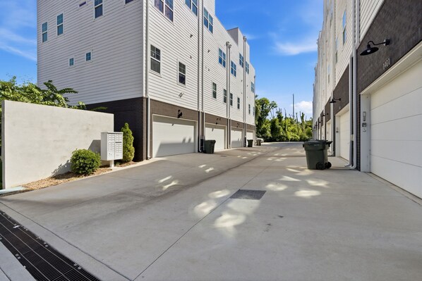 A modern building with multiple garage doors, a concrete pathway, and a clear sky.