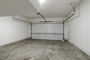 A garage with a concrete floor, white walls, and a closed garage door.