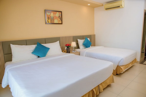 Two single beds with white linens and blue pillows, a nightstand with a lamp and a vase of flowers, and a painting on the wall. - Lanxy Nha Trang (Nha Trang)