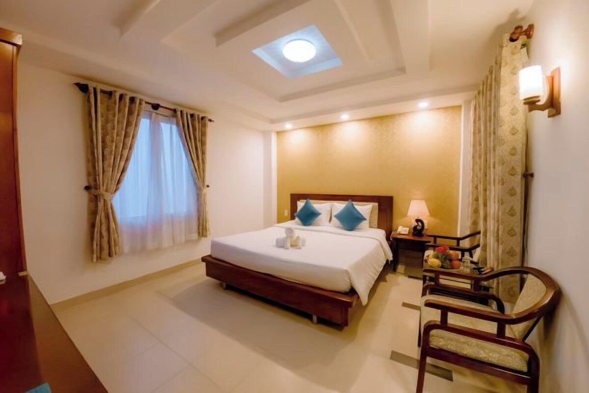 A hotel room with a bed, bedside table, lamp, and a chair.