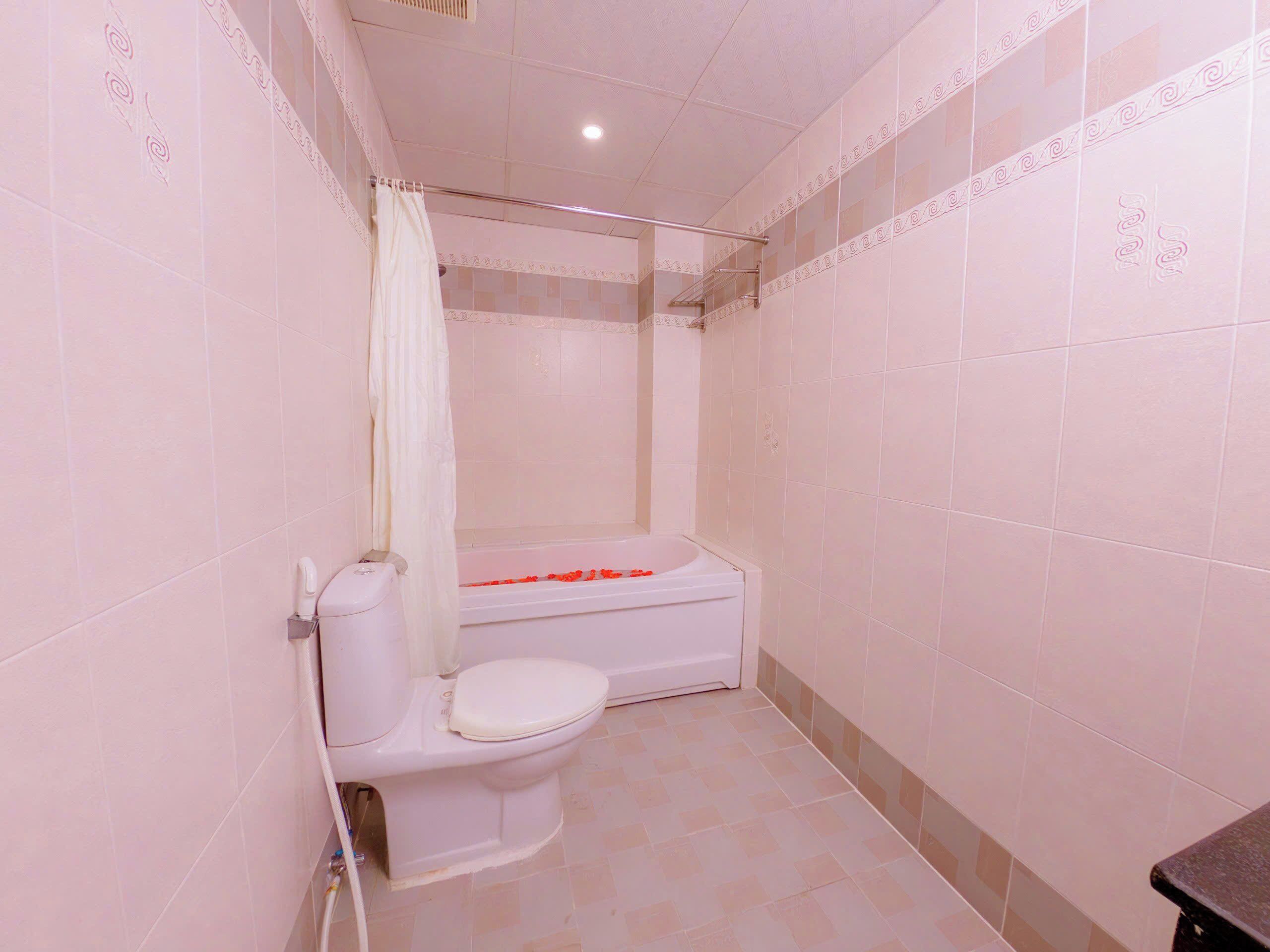 Une salle de bain équipée de toilettes, d’une baignoire et d’un rideau de douche.