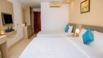 A hotel room with two beds, a TV, a desk, and a painting on the wall.