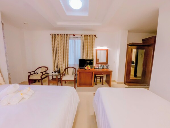 Une chambre d’hôtel avec deux lits, un bureau avec une chaise, une télévision et un miroir.
