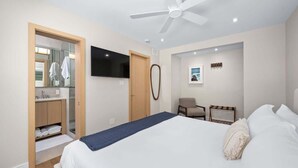 Une chambre d’hôtel équipée d’un lit, d’une télévision, d’un ventilateur de plafond, d’un bureau et d’une chaise.