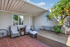 Un espace patio doté d’un coin salon abrité, d’une table et d’une plante en pot.
