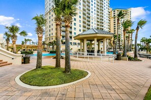 A resort area with palm trees, a gazebo, and a swimming pool.