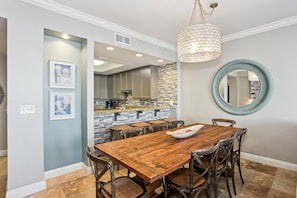 A dining area with a wooden table and chairs, a hanging light fixture, and a round mirror on the wall.