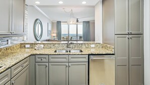 A modern kitchen with granite countertops, stainless steel appliances, and a view to the outside.