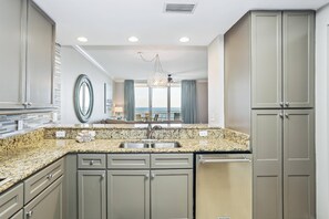 A modern kitchen with granite countertops, stainless steel appliances, and a view to the outside.