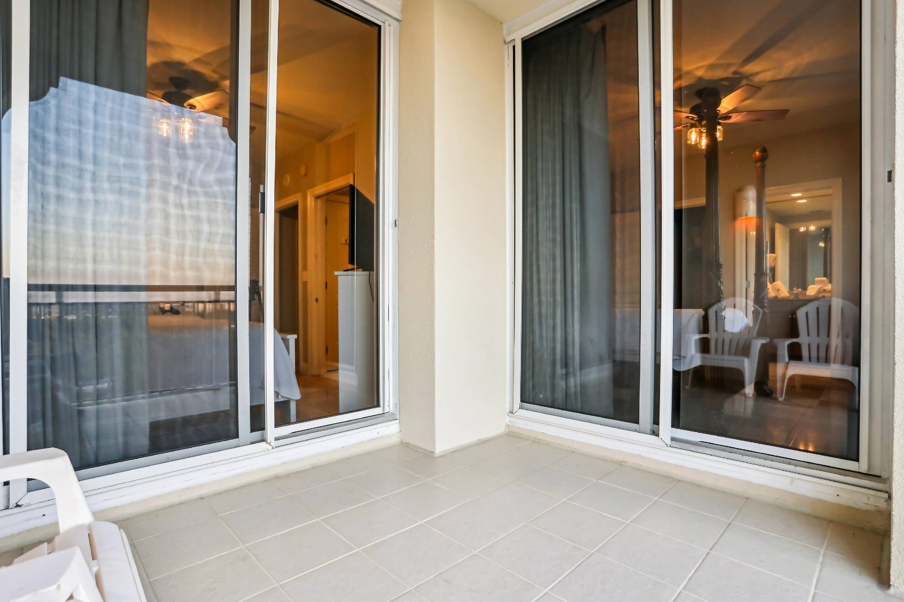 Ein Hotelzimmer mit Balkon, Schiebeglasfenster und Fliesenboden.