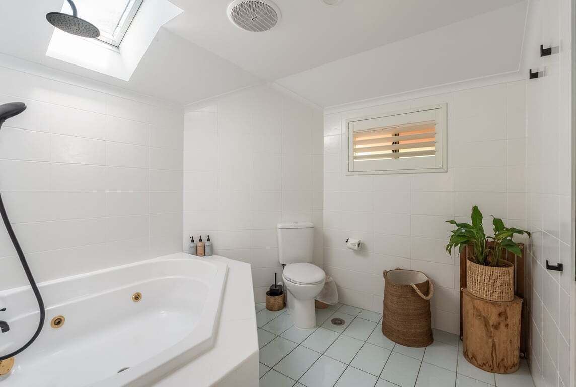A bathroom with a bathtub, toilet, and a skylight.