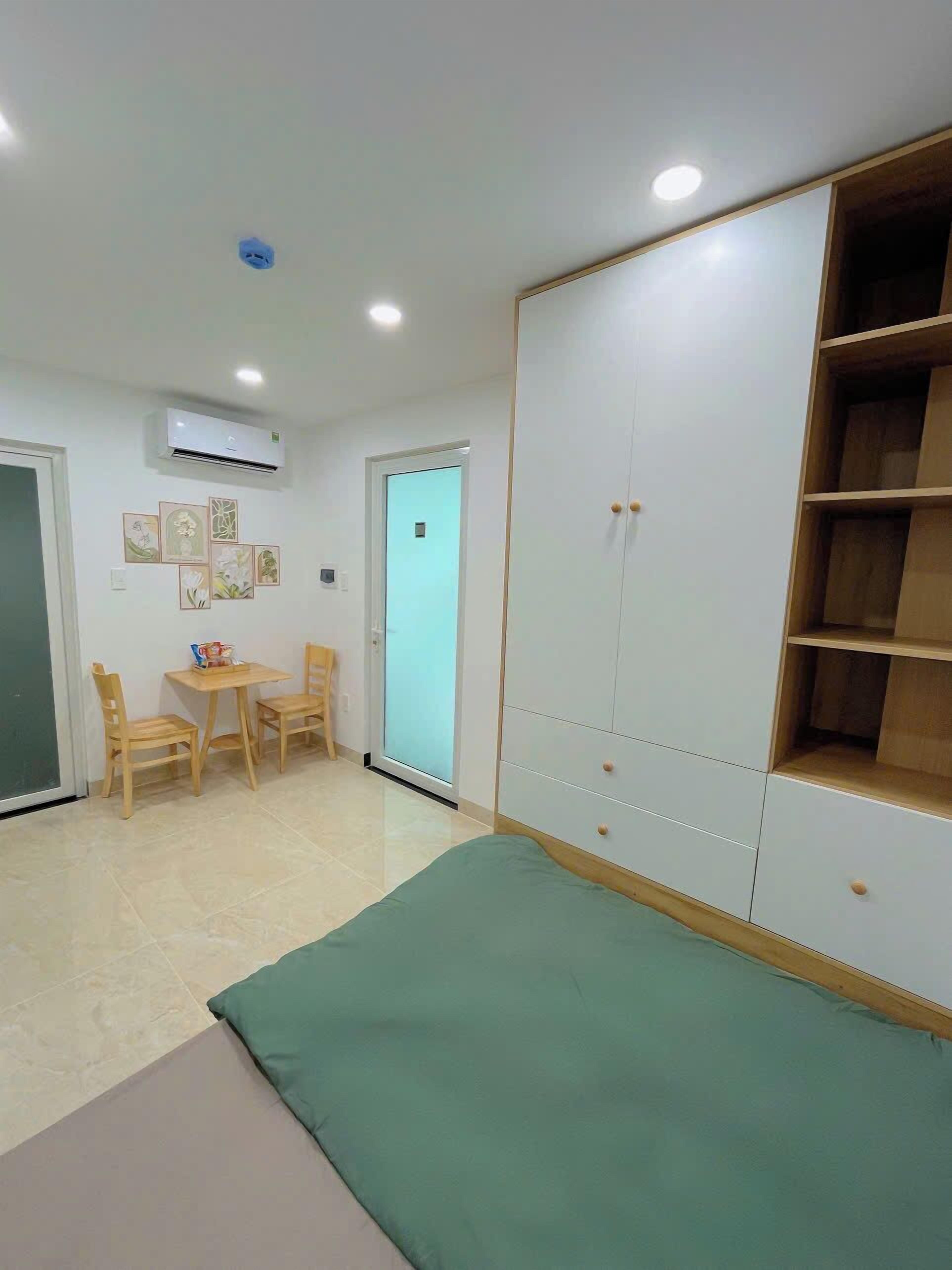 A room with a bed, a wardrobe, a desk with chairs, and a wall-mounted air conditioner.