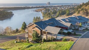 A residential area with houses, a river, and a distant rock formation. - Eagle's View - Luxury townhome. Amazing views. (Pacific City)