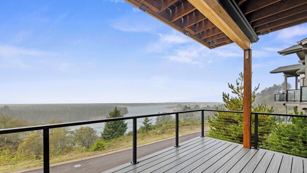 A wooden deck with a railing overlooking a road and a body of water. - Eagle's View - Luxury townhome. Amazing views. (Pacific City)
