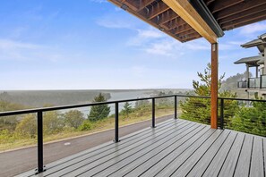 A wooden deck with a railing overlooking a road and a body of water. - Eagle's View - Luxury townhome. Amazing views. (Pacific City)