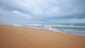 Una playa con una extensa orilla arenosa y olas acercándose a la costa.