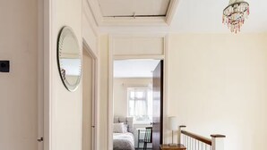 A hallway with a carpeted floor, a wooden railing, and a chandelier.