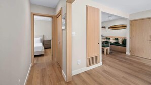 Eine moderne Wohnung mit Holzboden, einem Essbereich mit Tisch und Stühlen, einer Couch und einem Bett im angrenzenden Zimmer.