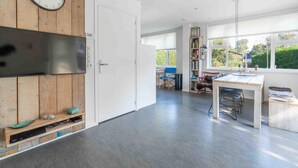 Eine moderne Küche mit einer Holzverkleidung, einer Uhr, einer Edelstahl-Dunstabzugshaube und einem Essbereich mit Tisch und Stühlen.