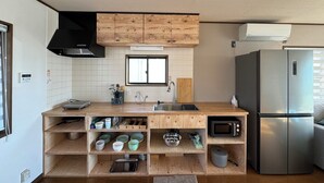 A modern kitchen with wooden cabinetry, a stainless steel refrigerator, and a built-in microwave. - Aoniwa - AWAJI (Awaji)