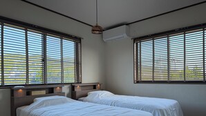 A hotel room with two beds, large windows with blinds, an air conditioning unit, and a pendant light. - Aoniwa - AWAJI (Awaji)