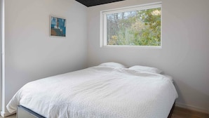 A bedroom with a bed, a window with a view of trees, and a painting on the wall. - 5 Star Holiday Home in Frederiksvaerk (Frederiksvaerk)