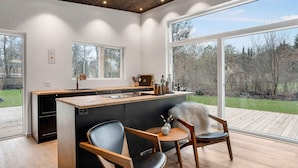 A modern kitchen with a large island, two chairs, and a view of the outdoors. - 5 Star Holiday Home in Frederiksvaerk (Frederiksvaerk)