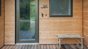 A wooden cabin with a glass door, a bench, and a window with the number 9A on the wall. - 5 Star Holiday Home in Frederiksvaerk (Frederiksvaerk)