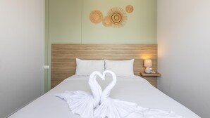 Una habitación de hotel con cama, cabecera de madera, mesita de noche con lámpara y decoración en la pared.