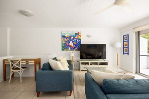 A living room with a TV, a painting, and a window.