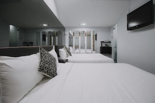 Una habitación de hotel con dos camas, un televisor de pantalla plana y un espejo.