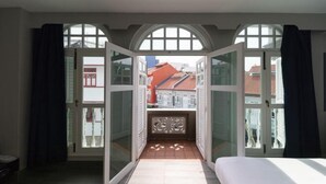 Une chambre à coucher avec un lit, une vue dégagée sur l’extérieur grâce à des portes ouvertes, et un sol carrelé.