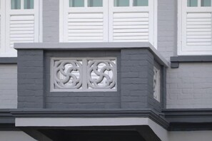 A building facade with a decorative window grille and white shutters. - Butternut Tree Hotel (Singapore)