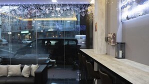 Un intérieur moderne avec un mur de verre, un coin salon doté de coussins et un comptoir de bar.