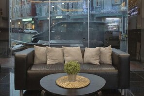 A leather sofa with patterned cushions, a woven placemat, and a small potted plant in front. - Butternut Tree Hotel (Singapore)