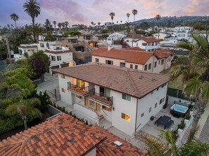 A residential area with houses featuring red-tiled roofs, balconies, and a swimming pool.