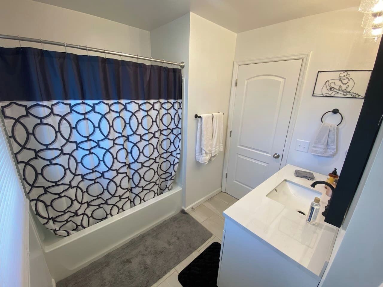 A bathroom with a shower curtain featuring a geometric pattern, a white sink with a mirror, and a towel rack.