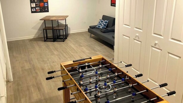 A room with a foosball table, a sofa, a coffee table, and a poster on the wall. - Paradise Found with Pool and Hot Tub (Nashville)