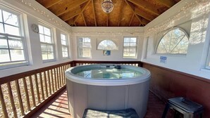 A hot tub in a covered outdoor area with wooden beams, a bench, and a small stool. - Paradise Found with Pool and Hot Tub (Nashville)