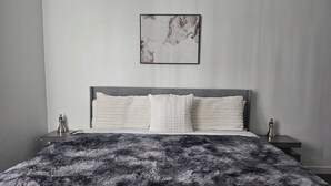 A bedroom with a large bed, two bedside tables, and a framed artwork on the wall.