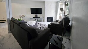 A modern living room with a flat-screen TV, a fireplace, and two sofas.