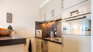A modern kitchen with stainless steel appliances, a wooden countertop, and a tiled backsplash.
