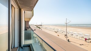 A balcony with a view of a beach and promenade. - Newly built flat with sea view (Koksijde)