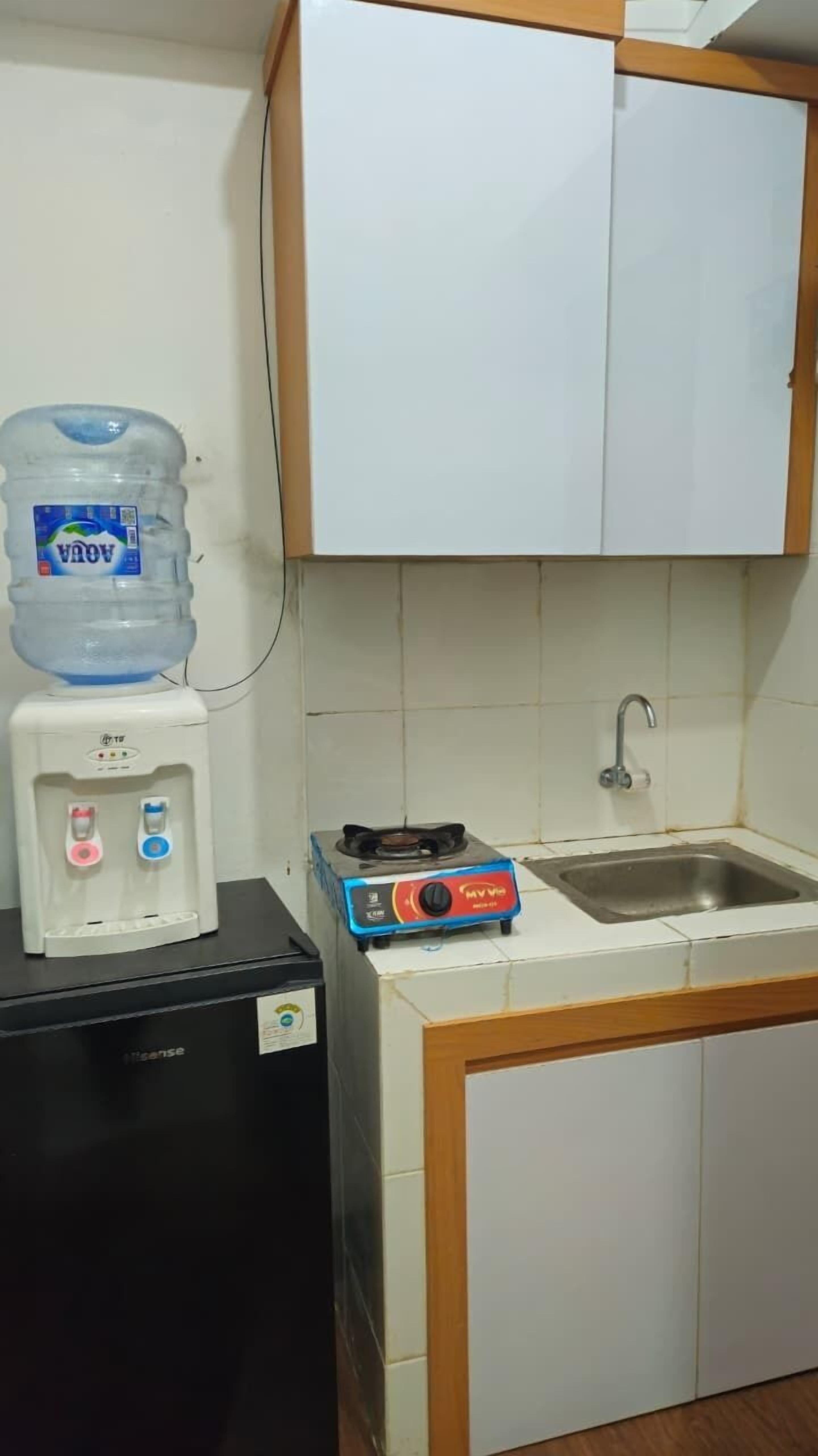 A compact kitchen with a water dispenser, a gas stove, and a sink.
