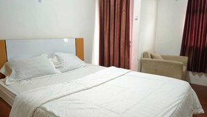 Una habitación de hotel con una cama grande, una silla y cortinas.