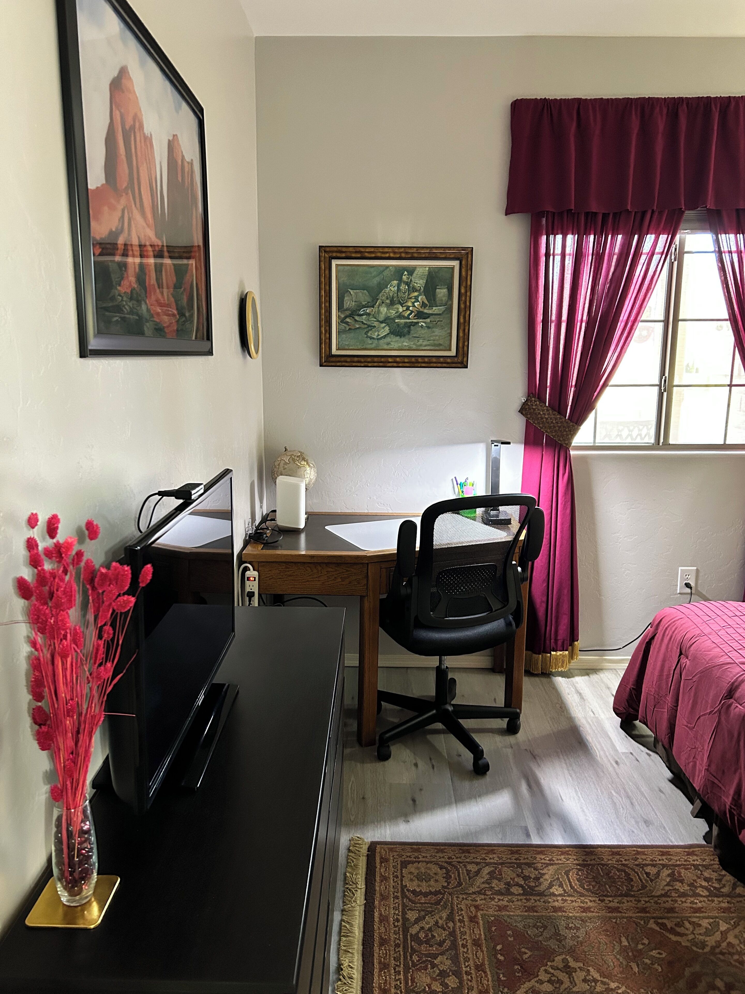 Una habitación con escritorio, silla, cama y ventana con cortinas.